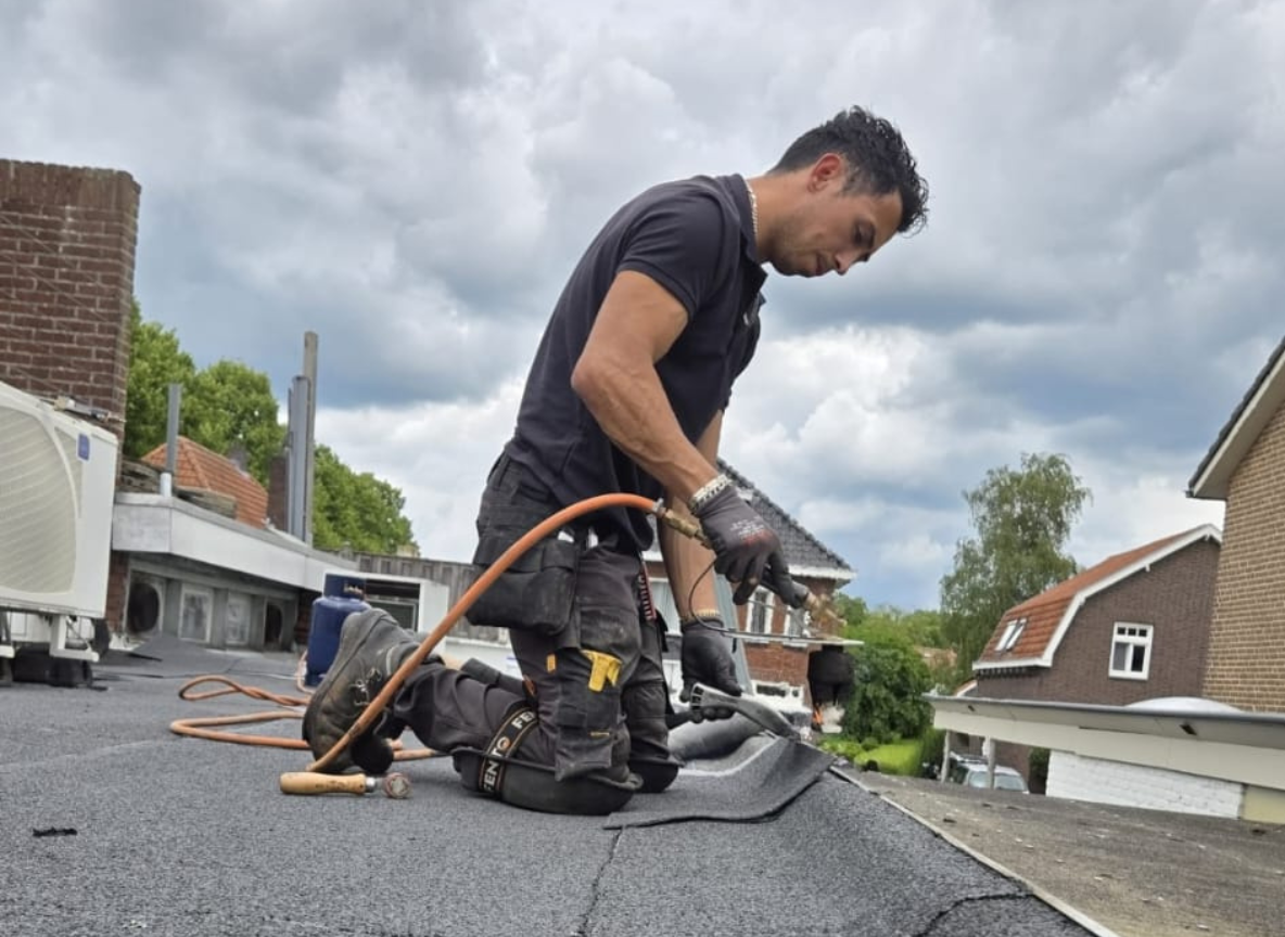 Dakdekker bezig met dakreparatie op plat dak.